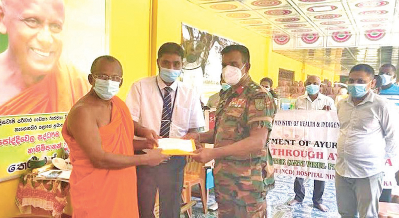 Chief Incumbent of the Deegawapi Parivara Ven. Bothivela Chandrananda Thera receiving the first pack of Ayurvedic medicines from Army Camp 241 Division Commander Colonel A.M.C. Abeyakoon and Nintavur Ayurvedic Research Hospital Acting Director Dr. K.L.M. Nagfer.