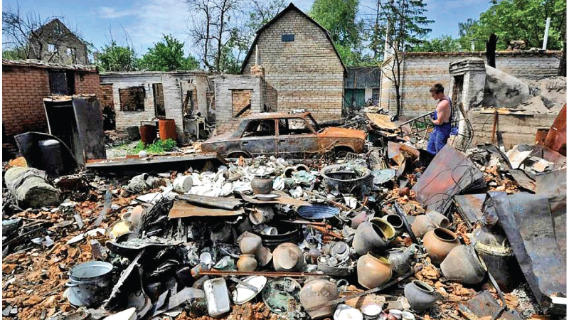 A man cleans up debris of his house destroyed by shelling in the village of Moshchun, Kyiv region, on June 2, 2022.