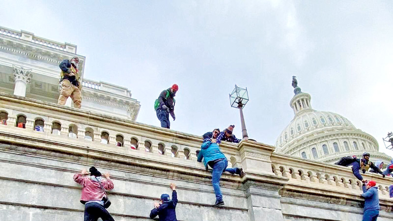 Donald Trump supporters climb a wall outside the Capitol building in Washingron D.C. after the 2020 Presidential election.