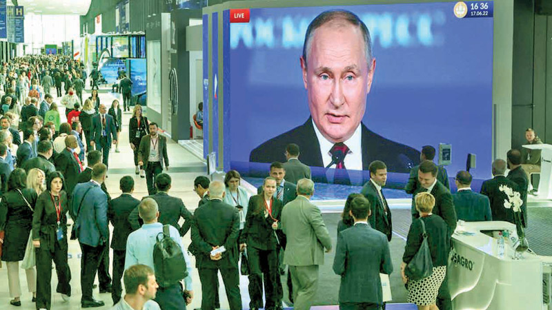 Participants gather near a screen showing Russian President Vladimir Putin delivering a speech at the St. Petersburg International Economic Forum (SPIEF) in Saint Petersburg, Russia  on Friday.