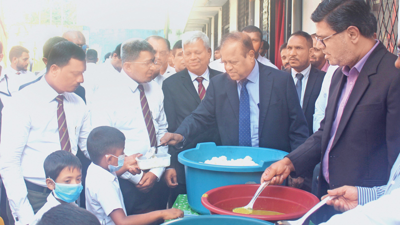 Minister Susil Premajayantha and MP Mujibur Rahuman providing food  for students during the visit. Picture by Ruzaik Farook