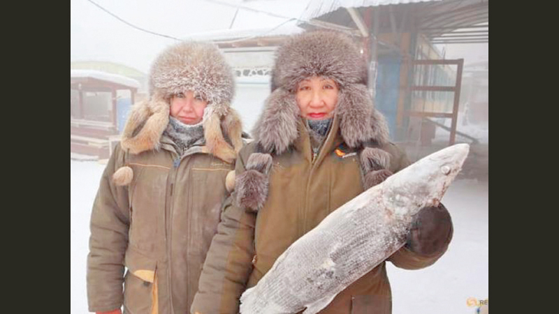 Marina Krivolutskaya and Marianna Ugai pose with a frozen fish at an open-air market on a frosty day in Yakutsk, Russia on Sunday.