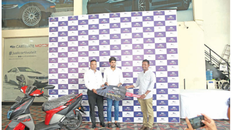 The winner of the TVS bike receives the key from officials of Creative Motors.