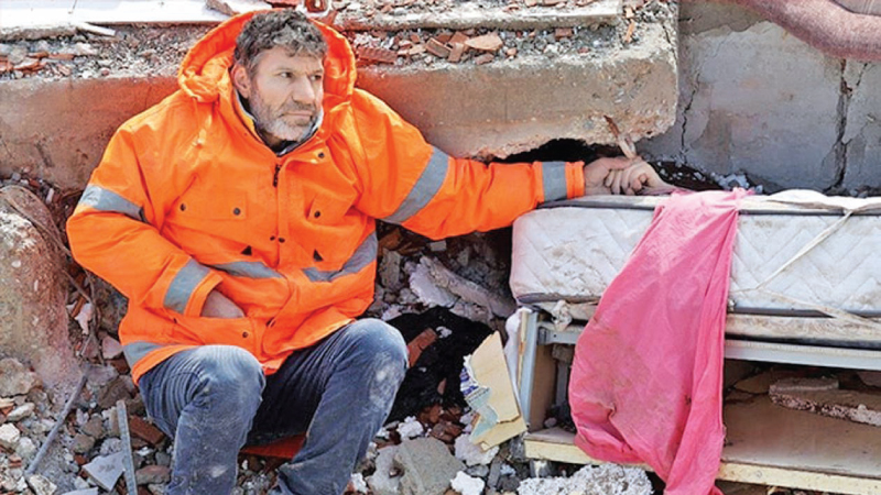 A man holds the hand of his 15-year-old daughter, who died in the earthquake.