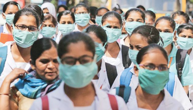 Indian nursing students wearing masks walk in a group at government run Gandhi Hospital in Hyderabad, India.