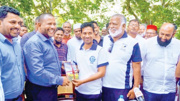 Industry and Commerce Minister Rishad Bathiudeen receives a copy of the book from author M.L.Sarifdeen at the event.