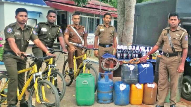 Police officers with the stock of illicit liquor they seized.