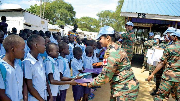 Personnel from the 8th Contingent of the Sri Lanka Army Medical Corps (SLAMC), United Nations Peace-Keeping Mission in South Sudan (UNMISS) distributing school books to children at an Internally Displaced People camp in Bor.